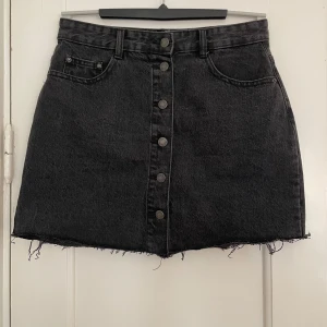 Jeanskjol med knappar - Jeanskjol med knappar hela vägen från Pull & Bear. Stl L enligt lapp men uppfattar den som en M. Mått enligt nedan: Midja mätt rakt över: 39cm Längd: 40cm 100% bomull, ingen stretch 