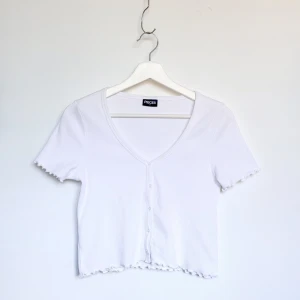 Vit sommartopp - En vit, somrig topp med knappar. Ribbat material. Storlek S. Från Pieces (Vero Moda). Toppen är kort men inte croppad. I bra skick!
