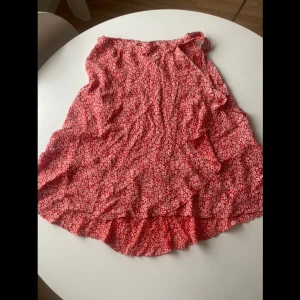 Kjol med volang  - Oanvänd kjol som knyts omlott i midjan. Går att justera i midjan så den funkar för en S också. 