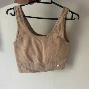 Sporttopp  - Beige sporttopp från drop of mindfulness. Superskön och har i/utagbara ilägg. Väldigt stretchig. Har lätt/medium support. Xs men hade passat S också.