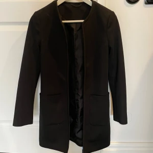 Kappa svart - Svart kappa inköpt 2019, tunn vår/ höst kappa, fickor fram, snygg med små detaljer, öppen i modellen. Tyvärr blivit för liten för mig i arm längd. 