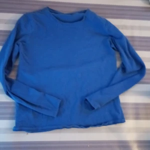 En blå långärmad tröja  - Den här tröjan är knappt andvänd och skulle passa bra till ålder från 9-11