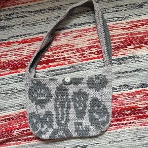 Virkad väska diy smiley crochet  - En liten handvirkad väska med smileymönster. Stängs med en knapp.  Har inget måttband så har lagt en pocket som storleksjämförelse. 