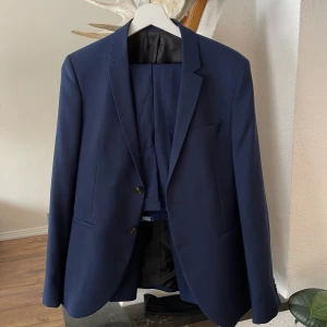 Jack & Jones kostym(byxor & kavaj)  - Jätte läcker kostym utan några defekter. Har används fåtal gånger. Storleken är 170cm på både byxorna och kavajen. Extra knappar följer med. På insidan av kavajen finns två fickor som går att stänga. Färg är marinblå. Pris kan diskuteras i dm.