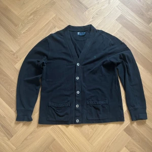 Polo Ralph Lauren cardigan - Fin cardigan från Ralph Lauren. Croppad passform/boxy med en skön mörkgrön/marinblå färg. Storlek M men fungerar även på S. I relativt använt skick men inte i dålig kondition. Den enda defekten är på den översta knappen (se bild 4).  100% bomull🤝  