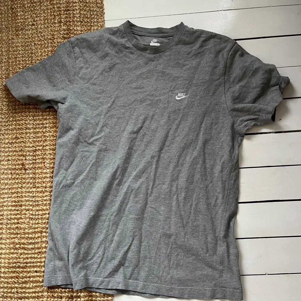 Unisex T-shirt från Nike. Grå och i använt skick. Storlek L. Nike-loggan är broderad. T-shirt i bomull. . T-shirts.