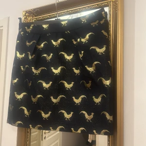 Mörkblå kjol med guldfåglar på! - Ovanlig kjol, medium kort i fint skick från klassiska Holly&Whyte!