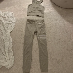 Oanvända Stronger träningskläder - Oanvänt träningsset från Stronger med både tights och topp. Därför i nyskick. Jättefin beige färg med vita detaljer. Nypris för både delarna tillsammans var 1100kr. 