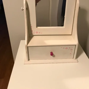 Spegel- pigtittare  -  H 40 cm B 28 D 12.. Vitmålad i trä med diskret blomster mönster och den har en liten låda. 