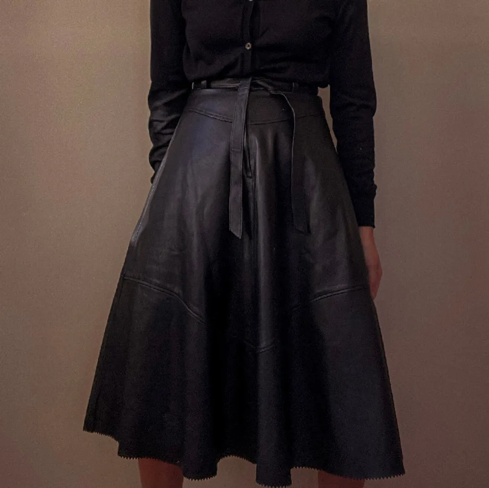 Vintage knee length leather skirt with raw hem. Back Zip Closure and Detachable Leather Belt, Fully lined. Feminine silhouette  Very Good Condition   Model Is 160cm (5'3