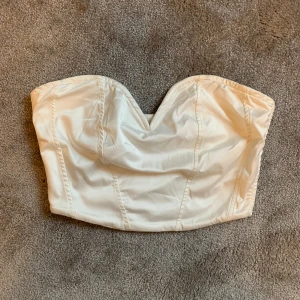 Vit korsett topp - Säljer denna vita korsett toppen från Gina Tricot 🤍 den har dragkedja i ryggen och är supersnygg med tex en blazer eller bara till fest 😍 bra skick! Obs den är rätt liten i storlek så passar xxs/xs! Hör av er vid frågor 