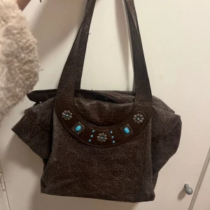 Skitsnygg vintage väska med stenar - Jättefin brun handväska med blåa stenar. Köpt second hand.  köparen står för frakten
