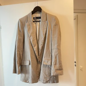 Linne Blazer från Zara - Fin blazer i linne från Zara. Använd enstaka gång. Säljer pga för kort i armarna. Jag är 178cm.  Funkar fint med uppvikta armar pga detaljmönstrad insida.   Säljer för 350kr. 