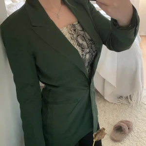 Grön kavaj - Snygg grön figursydd kavaj i silkes liknande material. Storlek 34 passar bra på mig som vanligtvis har 34/xs. I mycket bra skick inga slitningar eller hål. Kan behöva en strykning💕