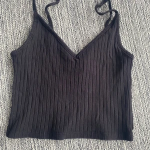 Svart vringat ribbat linne i strl xs från H&M - Svart vringat ribbat linne i strl xs från H&M.  Använd men i fint begagnat skick.  Mått Över bröstet: ca 32 cm Total längd: ca 41 cm  Bomull och elastan  Kommer från ett djur och rökfritt hem.