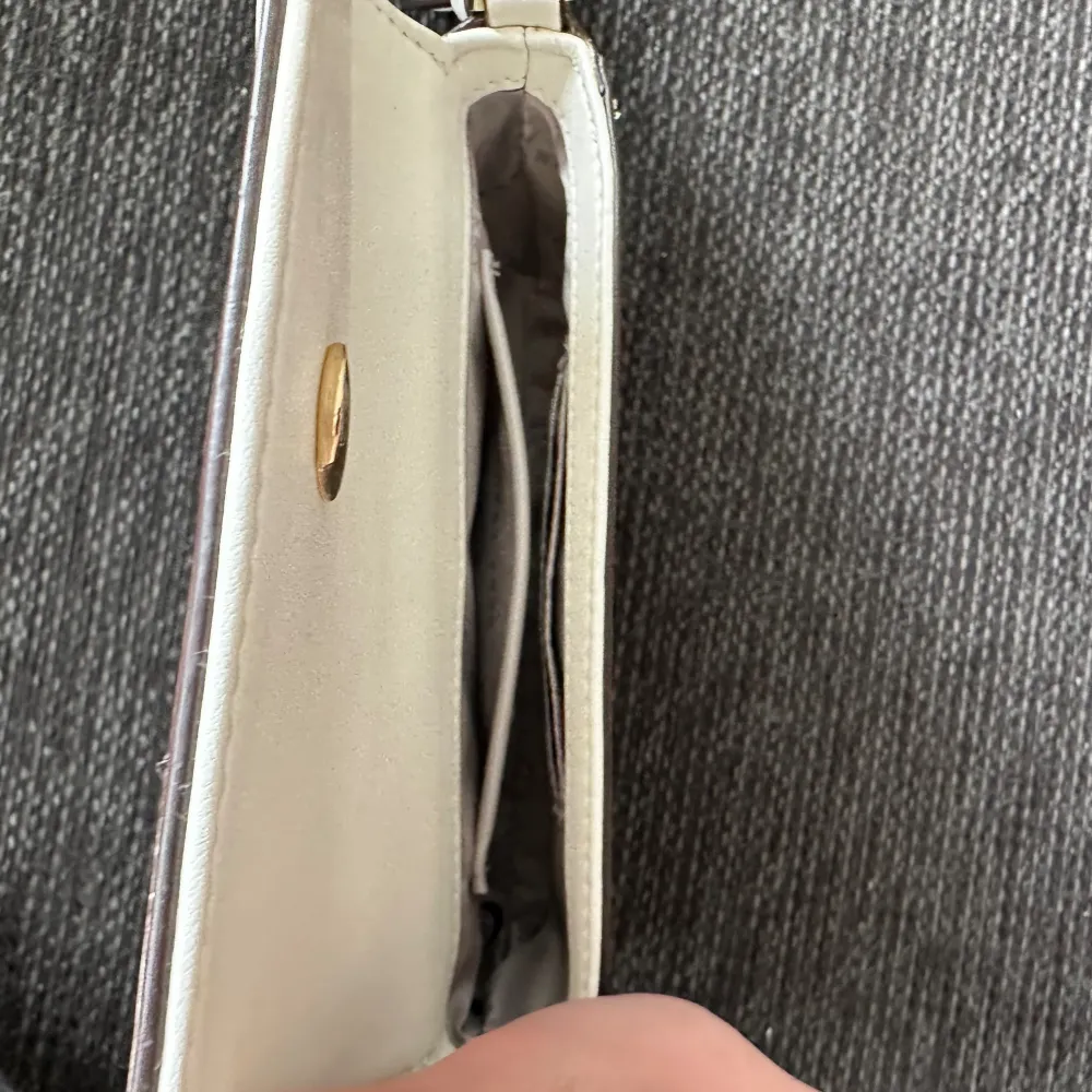 Vit Dkny väska med två inne fickar och en magnet stängd ficka på baksidan. Med justerbart band. Väskor.