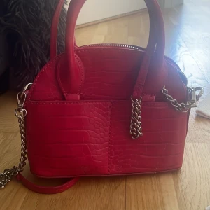 Väska  - Liten gullig röd/rosa väska aldrig använt då de ej e min stil länge! Men ny sick . Köpte för 400kr där av priset kan tänka mig sänka  Avtagbara kedjor!  Skriv vid intresse o fler bilder mvh 