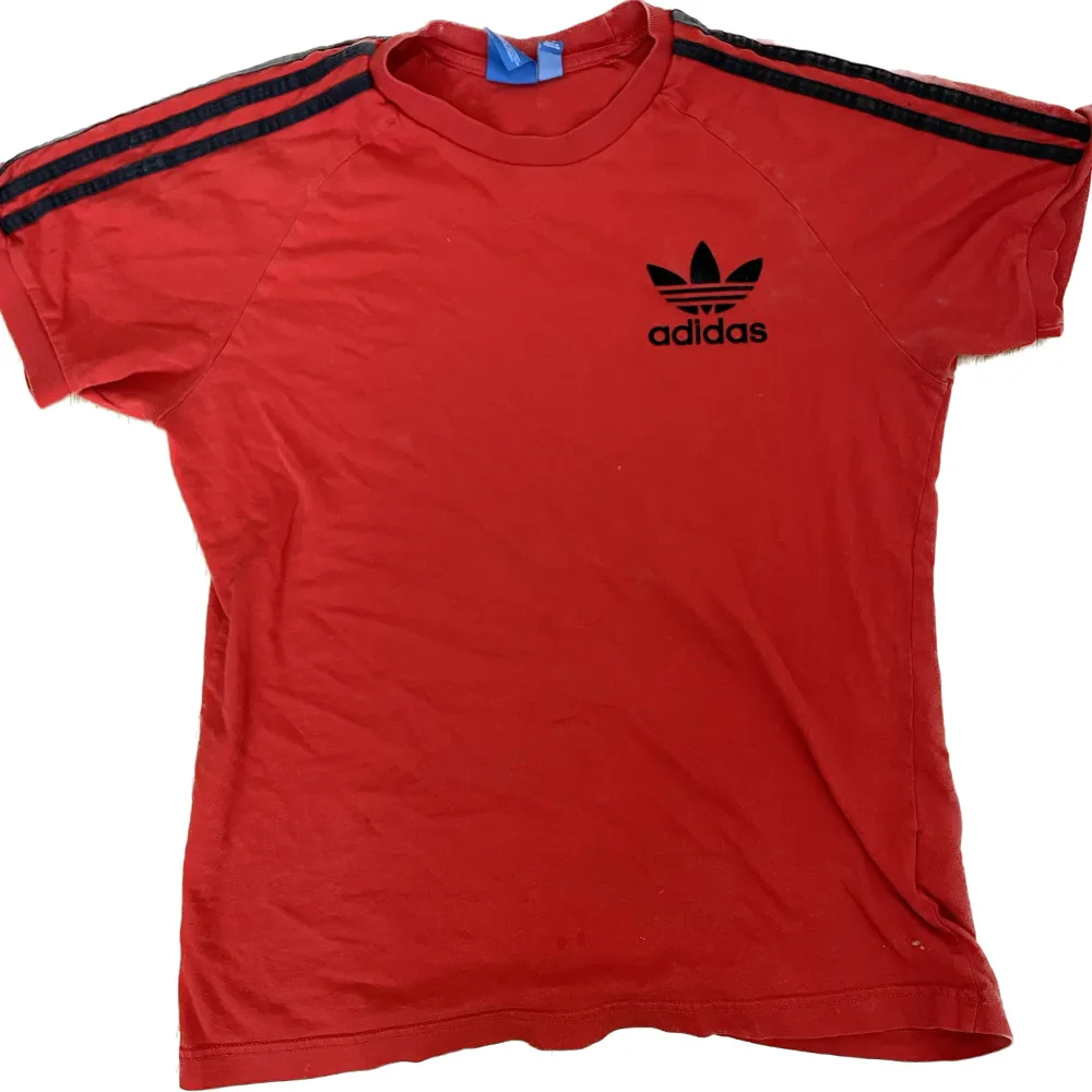 Röd adidastshirt med svarta detaljer, själva märket är i typ plysch? I bra skick, ränderna är möjligen en aning bleka.. T-shirts.