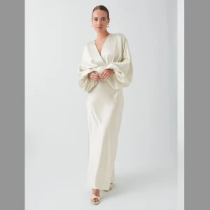 NY Vit lång satinklänning strl 40 med prislapp! - Oanvänd lång satinklänning i storlek 40 med voluminös ärm. Satinklänningen är vit och har glansig kvalitet. Den har lös passform upptill, figurnära kjol och dragkedja bak. Passar perfekt som en bröllopsklänning eller sommarklänning! 