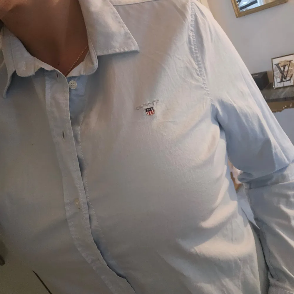 En stilren ljusblå skjorta från GANT med broderad logotyp på bröstet. Skjortan har långa ärmar och knappar framtill. Storlek 44 men är mer som en 42 alternativt 40. Skjortan är använd ca 4 gånger så nyskick! behöver strykas till lite :) . Paidat.