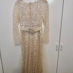 Exklusive champange guld klänning med bälte - Denna exklusiva klänning i en elegant champagne guld färg är perfekt för festliga tillfällen. Klänningen har ett stilfullt bälte som framhäver midjan och ger en sofistikerad look. Bra skick, pris kan diskuteras vid snabb affär 