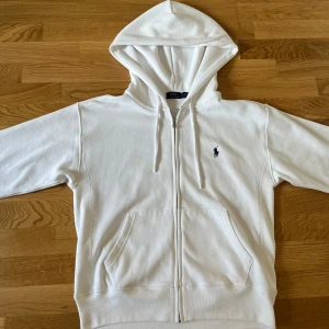 Vit Ralph Lauren Zip up - Hej säljer min helt nya Ralph lauren tröja för att den va lite för stor för mig. Har bara hafts på en gång. Extremt bra skick och är helt original, köptes från Zalando för 1500kr. Storlek M om ni har frågor skicka dm till mig så svarar jag snabbt💫