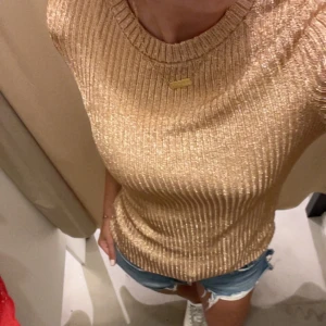 Glansig stickad t shirt  - Fin stickad topp som är glansig av sig. Tröjan är beige/ rosa och storlek S.