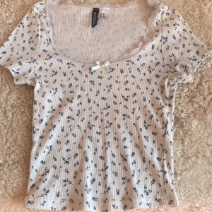 Urringad T-shirt med spets och blå blommor - Den är i mycket bra skick och bara använd några gånger, jag säljer den pga att den sällan används.