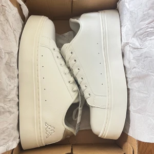 Vita sneakers  - Vita sneakers från kappa, logo isabel white-gray silver. Endast testade, aldrig använda. Lappen sitter kvar och skorna ligger i original kartongen. Köpta för 700kr, säljer för 500kr då dom tyvärr var försmå och jag hann inte lämna tillbaka i tid. 