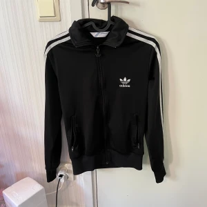 Kofta - Adidas kofta med polokrage och fickor som stängs med dragkedja 