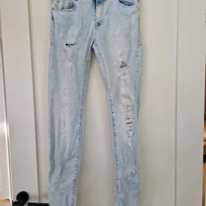 Jeans med slitningar  - Ljusa jeans med slitningar. Använda ett fåtal gånger, tvättade en gång inför försäljning. 2 små fläckar på låret (obehandlade) 