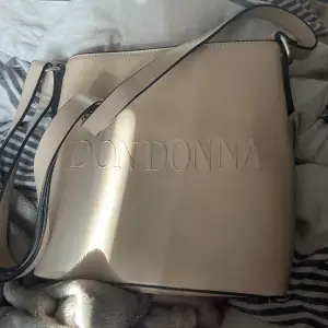 Don Donna väska i fin beige färg, sparsamt använd nästan i nyskick.   Hämtas i Karlshamn/Bromölla eller mot fraktkostnad.