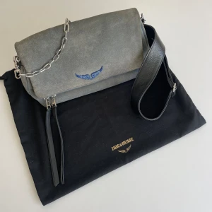 Zadig & Voltaire väska  - Zadig & Voltaire väska i modellen Rock i blå mocka. Använd men i mycket bra skick. Mockan är lite blekare på utsidan än insidan. Finns två axelband, en lite kortare kedja och en längre i svart läder. Köpte den för runt 3600kr, säljer den för 1950kr.