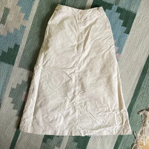 Retro beige midikjol Dobber - Vintage fin lång kjol från Dobber, trevlig beige färg med gylf och dekorativa knappar i sidan.   Märkt storlek 8 = 36, kollar gärna måtten eftersom det är vintage.   Måtten är mätta platt rakt över.  Midja: 27,5  Höft/Stuss: 39 Längd: 69