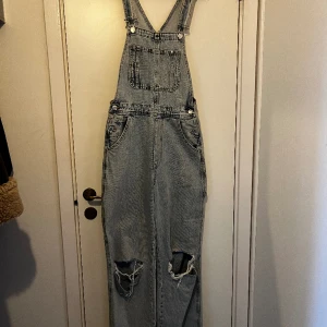 Hängselbyxor - Hängselbyxor från H&M med hål vid knäna. Sällan använda. Storlek 34. Tveka inte att höra av dig om du har frågor 