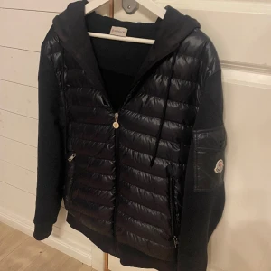 Moncler cardigan - Säljer en sjukt fet marinblå moncler cardigan i den sällsynta och eftertraktade modellen ”Maglia con cappucio”. Skick 8,5/10 (inga deffekter utöver lite smått solblekt tyg). Storlek L men passar bra på M då moncler oftast är rätt så små i storleken. 