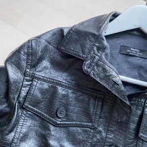 Svart top  - Svart kort tröja i skinnimitation från bershka. Aldrig använd. Säljs då den var för liten. 