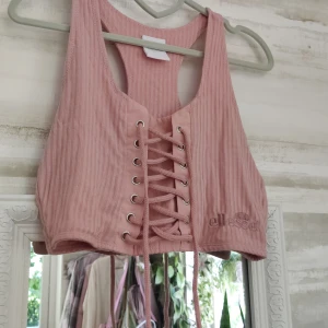 Crop top i viskos från Ellesse - Oanvänd, en lite beigare ljusrosa, mjukt och bekvämt tyg. Strl M men går att justera tack vare snörningen. Bild 2 och 3 visar färgen bättre, enligt min mobil iallafall. 