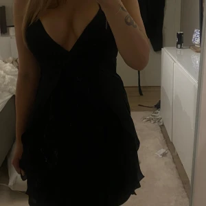 Silky Ruffled Little Black Dress - Brand: Lipsy London SIZE: 10 Im selling this sadly because it’s too thigh around the chest area for me to be able to use. It has a hidden zipper in the back and dress is a little longer in the back with some details depicted in the one of the picture