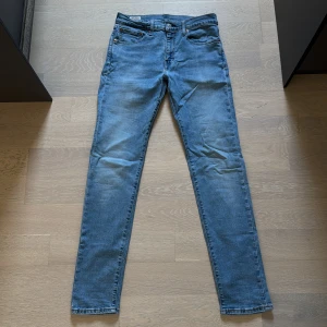 Levi’s 512 Ljusblå - Jeansen är tvättade och använda. De har även en liten färgstänk på ena knäet, men som knappt syns.