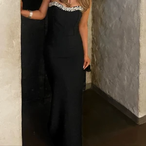 Svart långklänning/ Balklänning - Svart klänning med kristaller på som jag använde till min bal men man kan använda den till när man vill. Klänning är bekväm att ha på sig, ger en fin form och har slits på vänster sida.  Endast använd 1 gång🌸