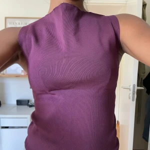 Mörklila Topp - Mörlila topp med hög krage. Säljes då den köptes men aldrig kom till användning. Modell bär vanligtvis XS/S och är 165cm
