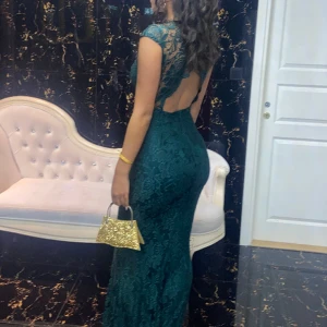 Balklänning - En klänning i spets som är åt det mörkgröna hållet. Det är storlek 38 men den är insydd i midjan. Jag är 178cm.