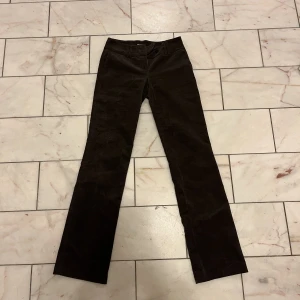 Bruna flare/bootcut byxor - Bruna byxor i Manchester med lite tryck vid rumpan och låret. Midjemått 40 och längd 106! En knapp av tre är borta men sitter extra knappar på tagen så det är bara att sy dit. Har kunnat använda dem utan den extra knappen också, skriv för bild på det! 