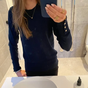 Tunn stickad tröja - Säljer denna fina mörkblåa stickade tröjan i lite tunnare material. Köpt på Lindex men märket är Holly and Whyte.Nästan inga defekter förutom att guldknapparna på ärmarna har tappat lite färg. Nypris 349, säljer för 110 + frakt😊