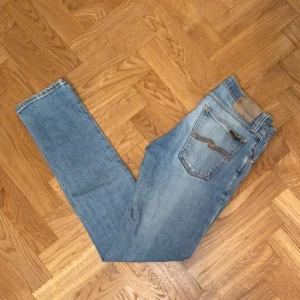 Nudie jeans - Säljer dessa sjukt feta Nudie jeans! As najs ljusblå/ grå tvätt, storlek W29 L32. Finns ett slitage märke på höger ben, se bild 3 men inget som drar ner skicket!