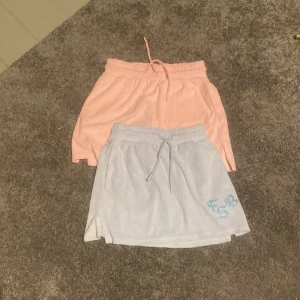 2st kjolar - Det är ett skelett av en fisk i bak på den blåa och det står ”bozzy” på den rosa i bak. Storlek: XS men är stretchiga.
