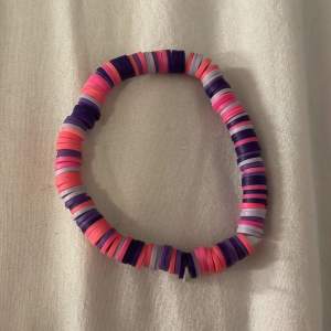 Ett pärlat armband i lila och rosa 