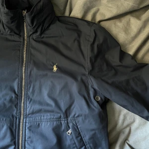 Ralph Lauren Jacka - Säljer en ritkigt snygg Ralph Lauren jacka i hög kvalite som funkar bra till våren nu när de börjar bli lite varmare. Finns även en luva inuti jackan som man kan ta ut. Super bra skick, sparsamt använd. För fler bilder & frågor, hör av er, tack!