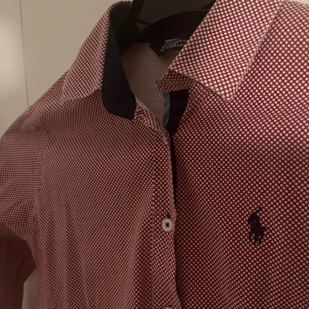 En stilig Polo Ralph Lauren skjorta för dam i röd med design(zooma in). Använd men bra skick, kan behöva strykas lite men inget mer. Storlek 38 passar S och Xs. Skjortor.